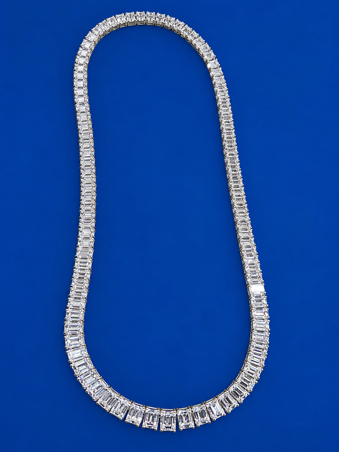 Emerald cut diamond line necklace displayed on a blue background