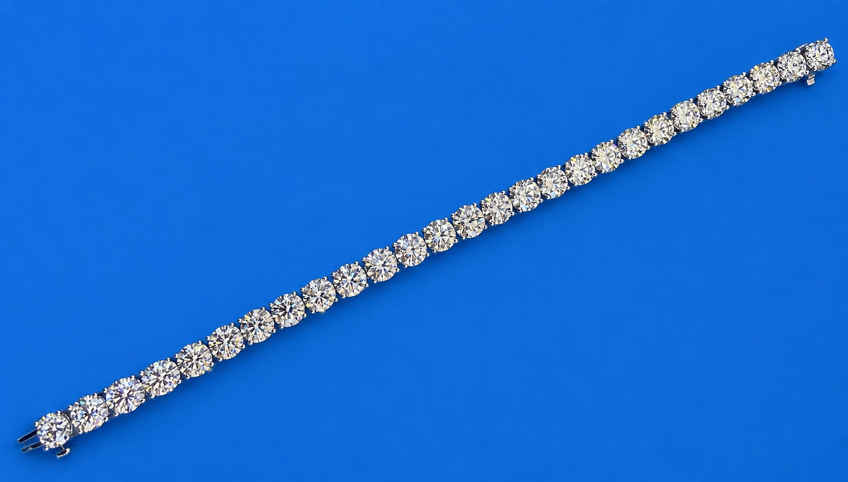 Round brilliant diamond bracelet in a white metal setting on a blue background